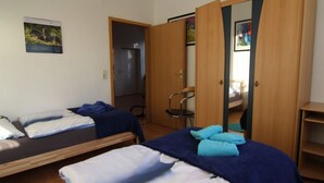 Een kamer met twee bedden, een stoel en een kast.