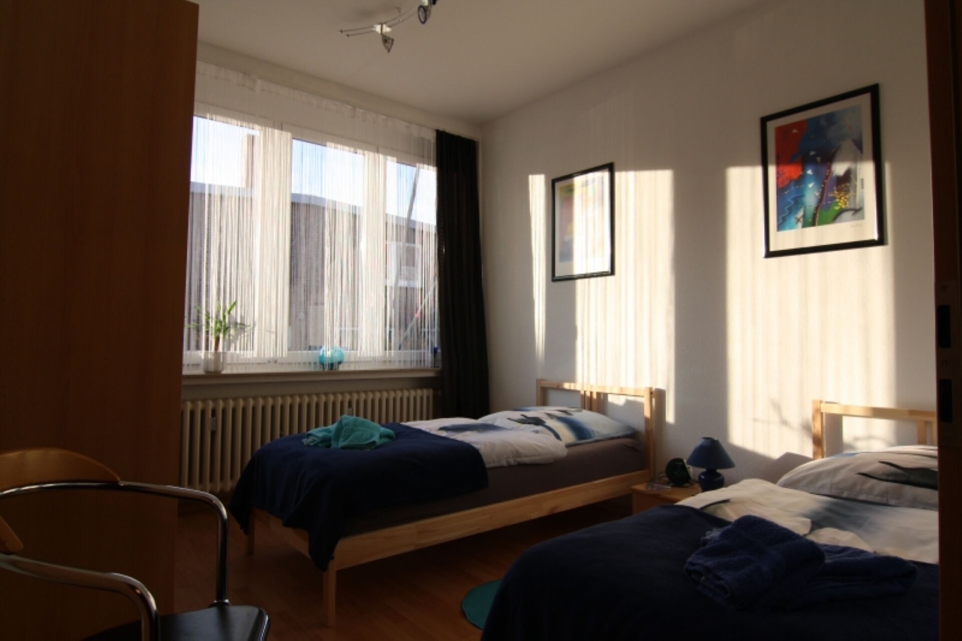 A bedroom with two single beds, a chair, and a radiator.