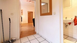 Een gang die leidt naar een badkamer met een wastafel en een spiegel.