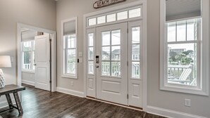 A hallway with a wooden floor, white doors, and a sign that reads "BEACH HOUSE". - Luxury Home with PRIVATE POOL!  Pet Friendly and Wifi (North Myrtle Beach)