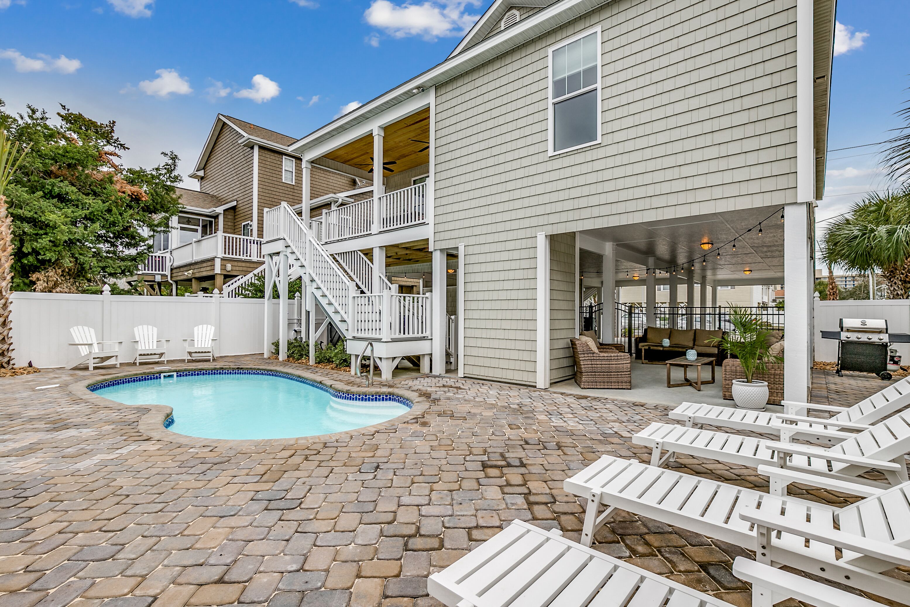 Une maison à deux étages avec une piscine, un espace extérieur aménagé et un coin barbecue.