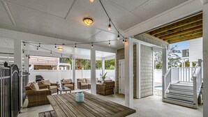 An outdoor patio area with a wooden table and wicker furniture, string lights, and a view of the house. - Luxury Home with PRIVATE POOL!  Pet Friendly and Wifi (North Myrtle Beach)