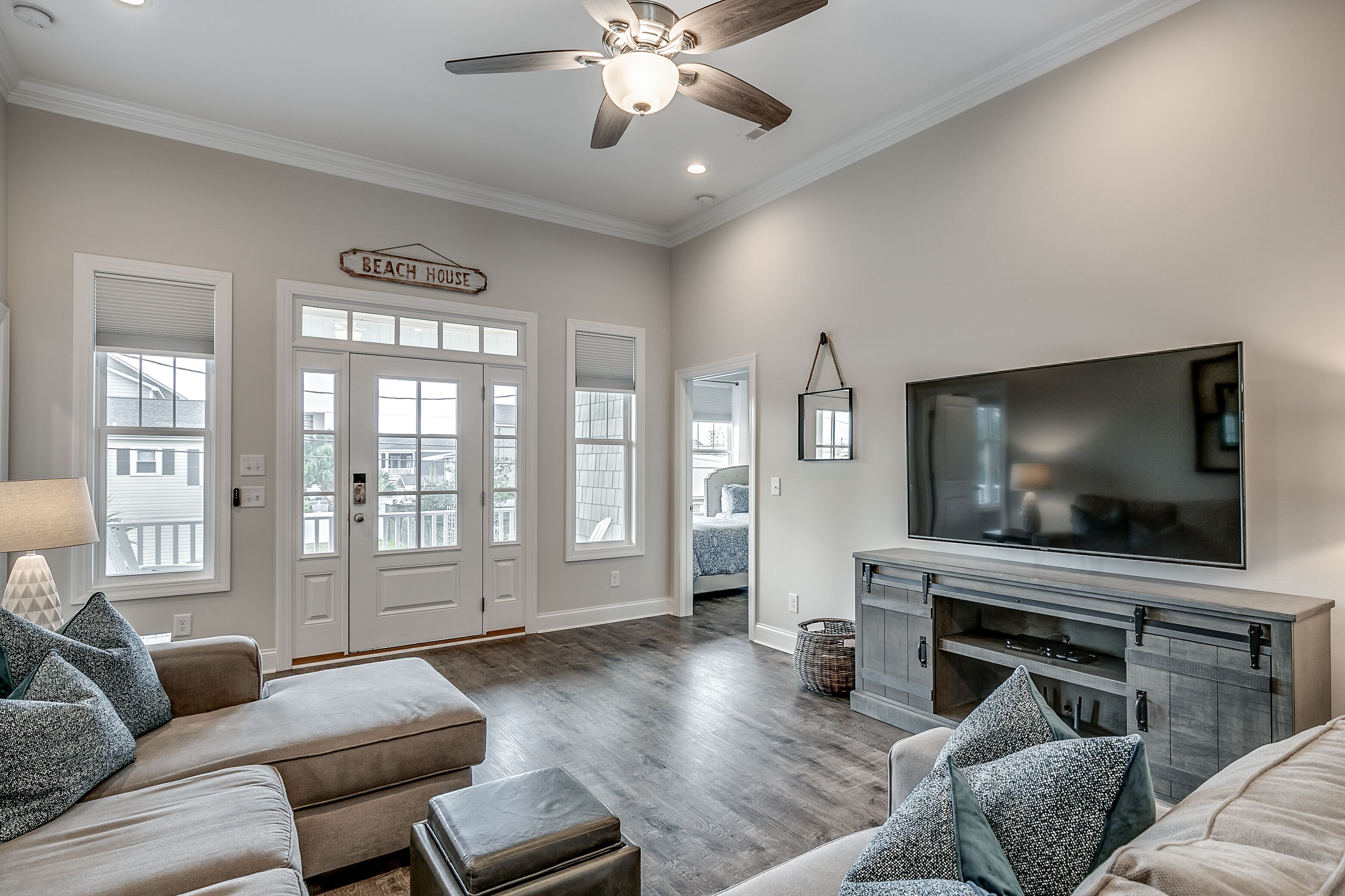 A spacious living room with a large flat-screen TV, a fireplace, and a ceiling fan.