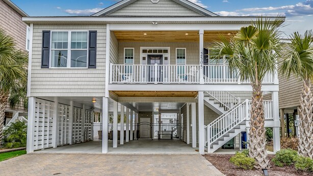 A two-story house with a balcony, a covered entryway, and a staircase leading to the upper level. - Luxury Home with PRIVATE POOL!  Pet Friendly and Wifi (North Myrtle Beach)