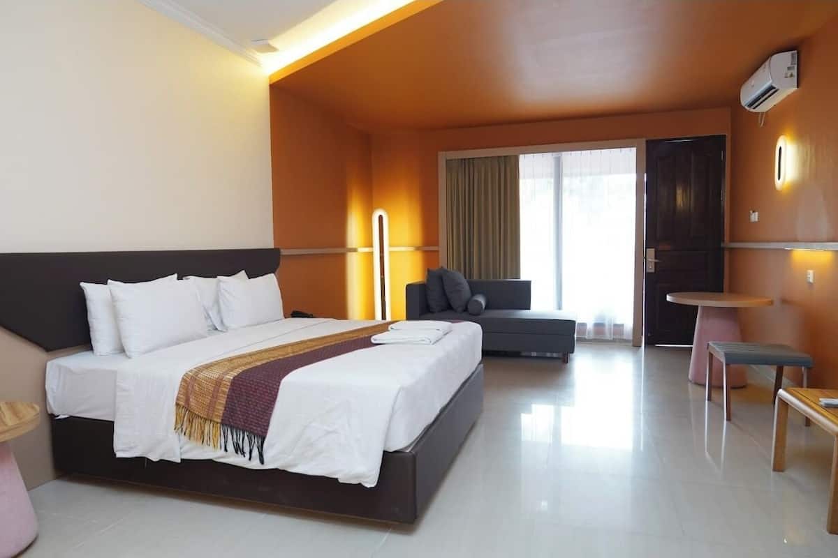 A modern hotel room with a large bed, a sofa, a small table, and a chair.