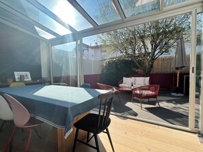 A sunlit patio with a table, chairs, and a sofa.