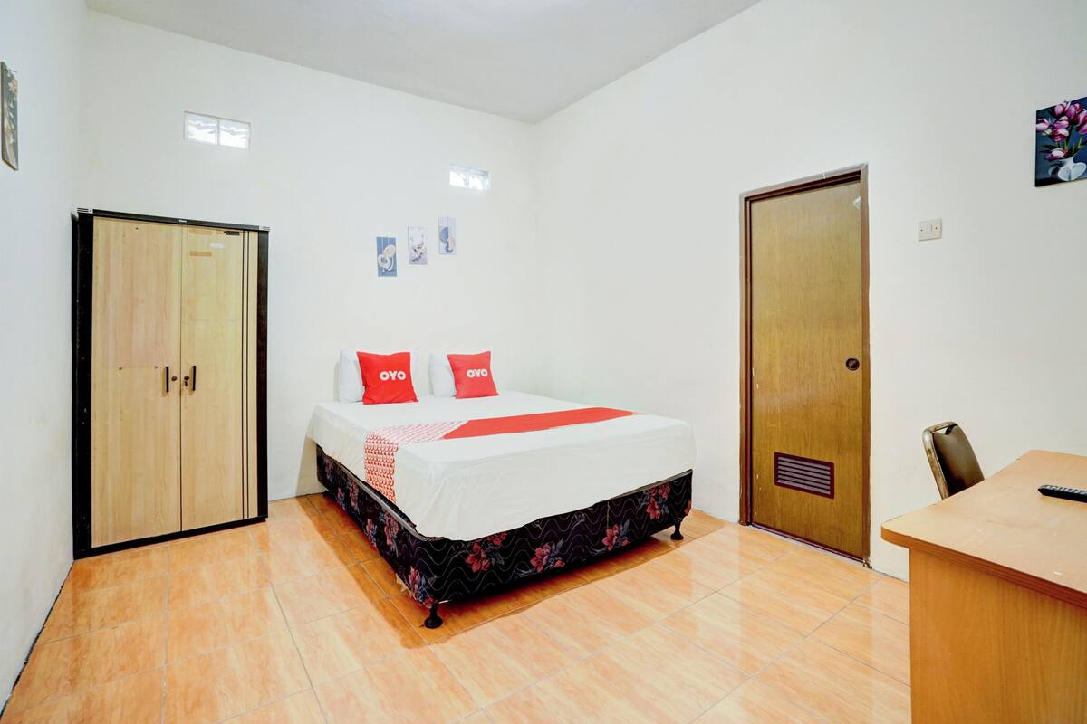 A bedroom with a bed, a desk, and a wardrobe.