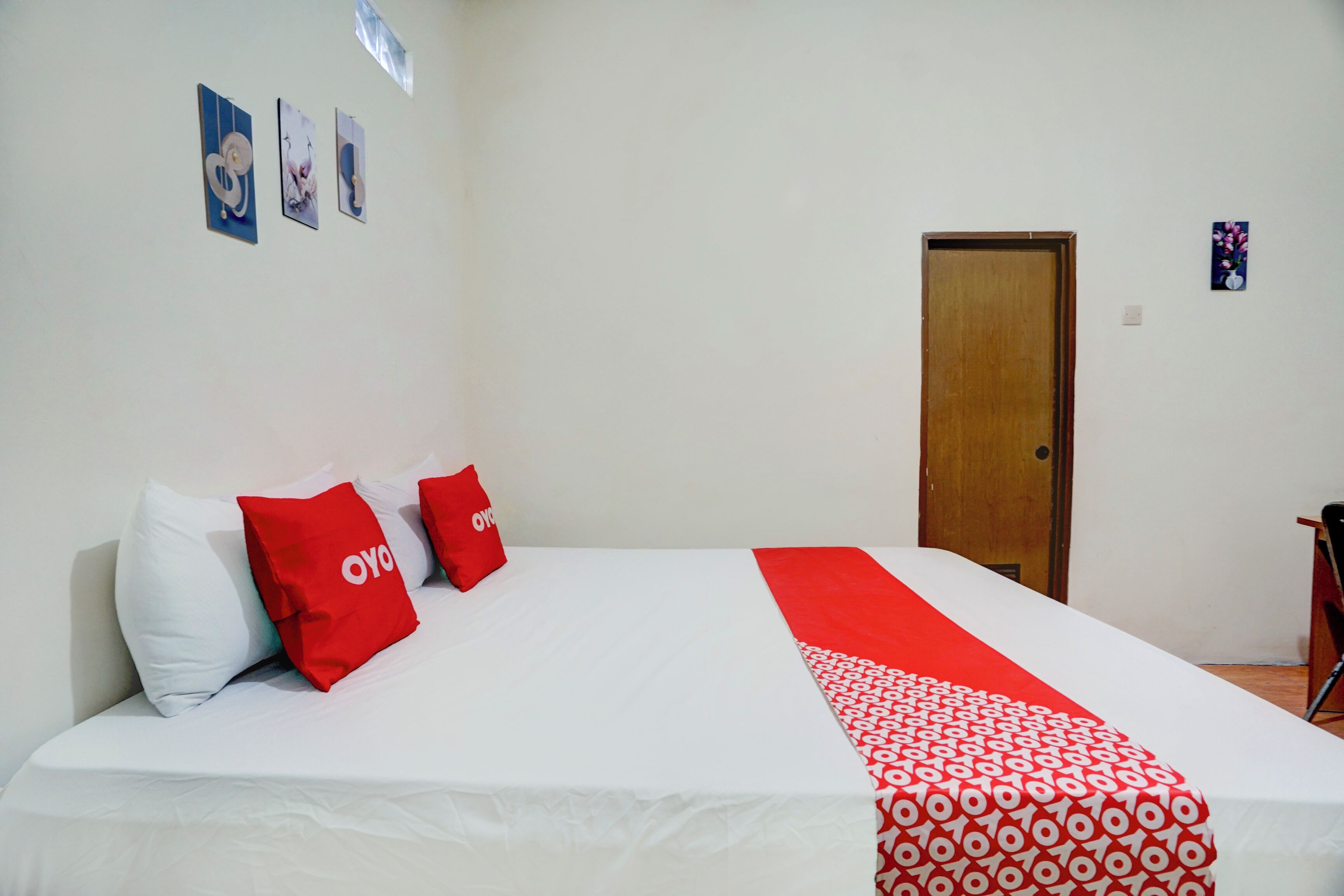 Ein Hotelzimmer mit einem Bett, einer Holztür und Wandbildern.
