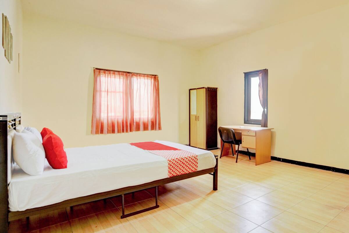 A bedroom with a bed, a desk, and a wardrobe.