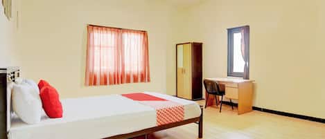 A bedroom with a bed, a desk, and a wardrobe.
