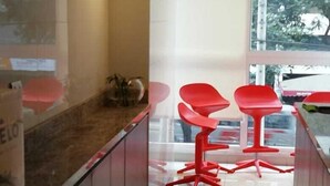A modern kitchen with a marble countertop, red bar stools, and a large window offering a view of the outdoors.