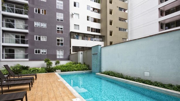 A rooftop pool area with lounge chairs and a view of surrounding apartment buildings.