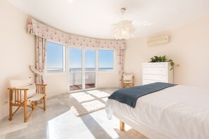 A bedroom with a large window, a bed, a dresser, and a chair. - Villa Panorama – Ocean View Oasis with Private Pool, Mijas Costa (Mijas Costa)