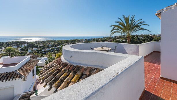 A rooftop terrace with a curved white wall, a small table and chairs, and a view of the sea and surrounding buildings. - Villa Panorama – Ocean View Oasis with Private Pool, Mijas Costa (Mijas Costa)