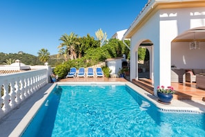 A swimming pool with blue water, surrounded by white columns and blue lounge chairs. - Villa Panorama – Ocean View Oasis with Private Pool, Mijas Costa (Mijas Costa)