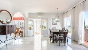A spacious room with a marble floor, a dining area with a wooden table and chairs, a large mirror, and a view of the outdoors through large windows. - Villa Panorama – Ocean View Oasis with Private Pool, Mijas Costa (Mijas Costa)