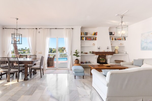 Amplia sala de estar con mesa de comedor, sillas, sofá y estantería.