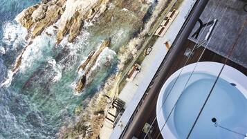A high vantage point view of a coastal area with a swimming pool and a rocky shoreline.