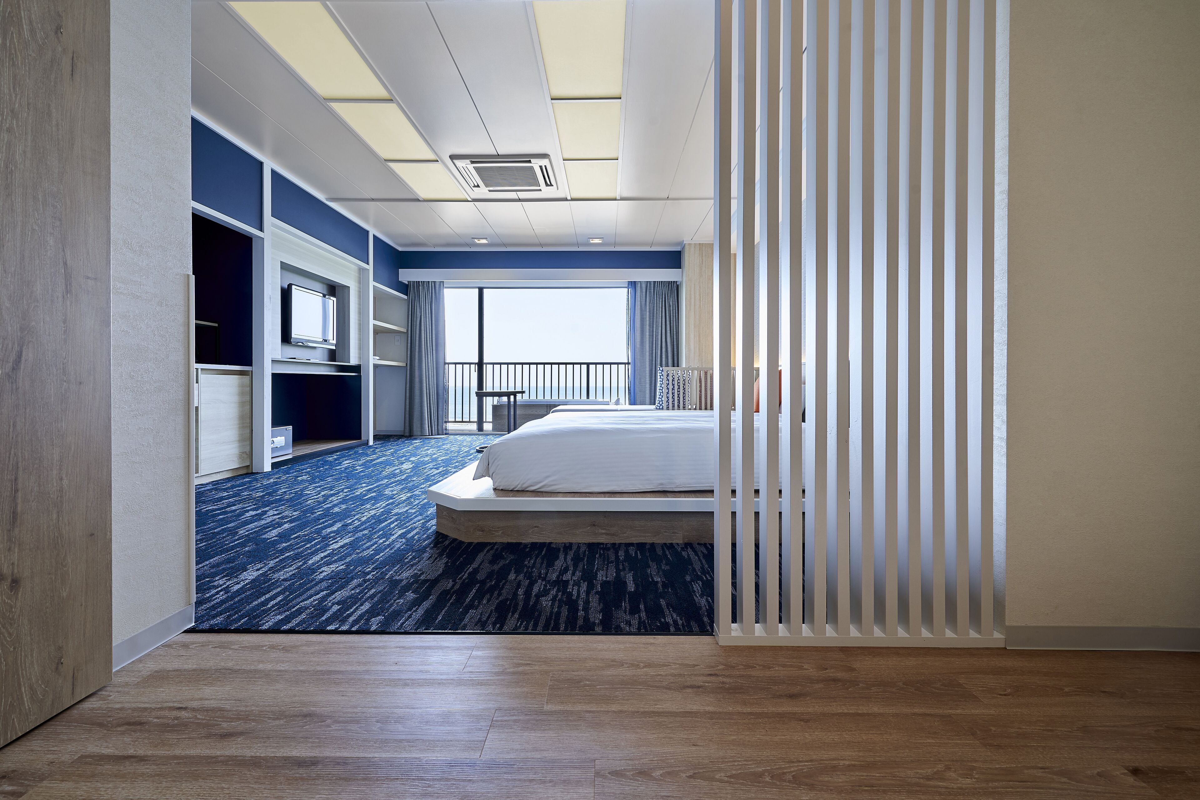 Una camera d'albergo moderna con un letto grande, una televisione, una scrivania e vista sull'esterno.