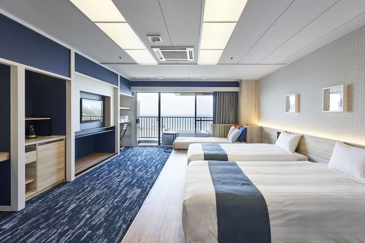 Una habitación de hotel con balcón, escritorio, cama y televisor.