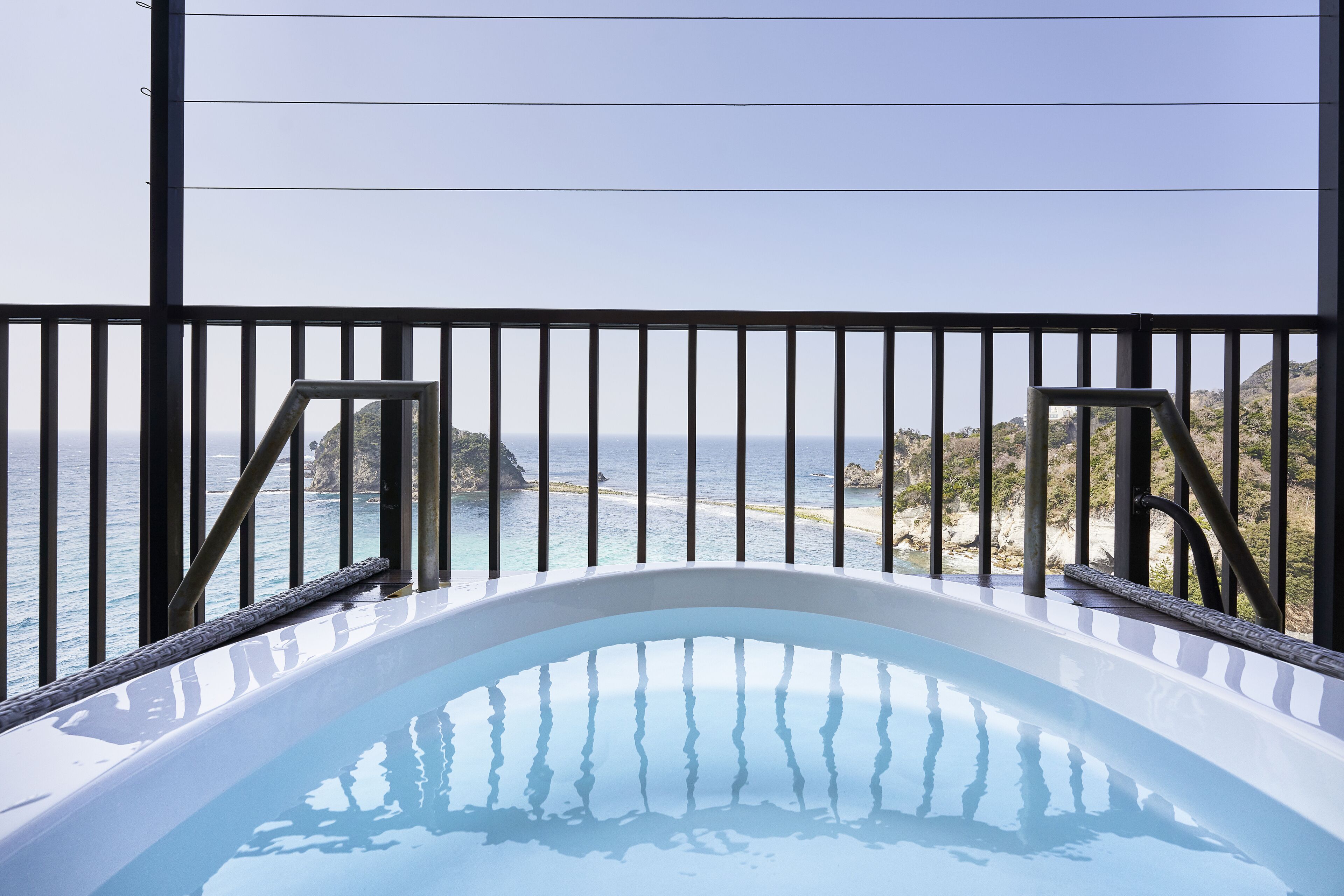 A hot tub with a view of the ocean and a rocky landscape.
