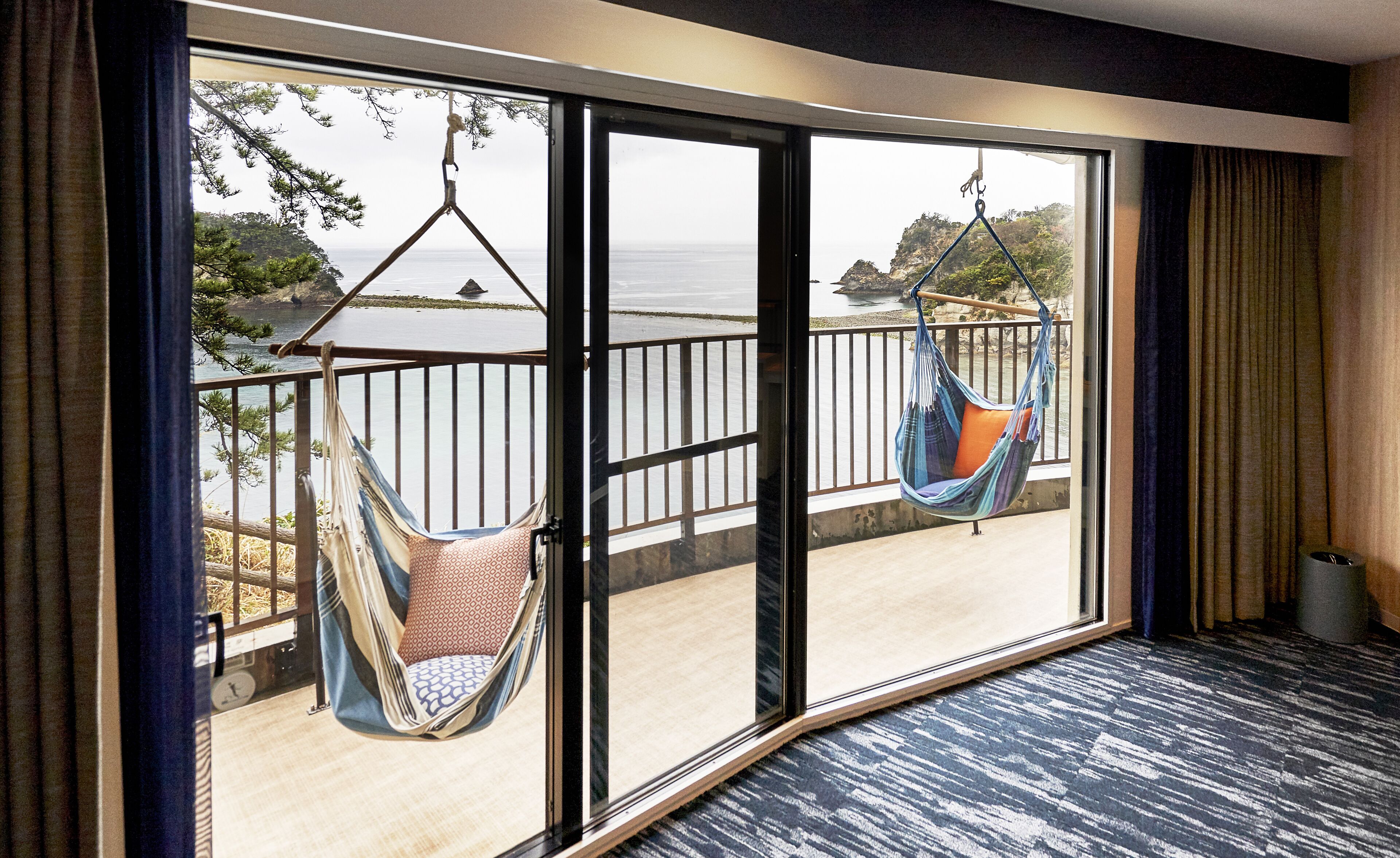 A room with large sliding glass doors leading to a balcony with two hammocks.
