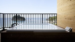 Une cabane en bois dotée d’un balcon, d’un jacuzzi, d’une vue sur la mer et d’une petite île visible au loin.