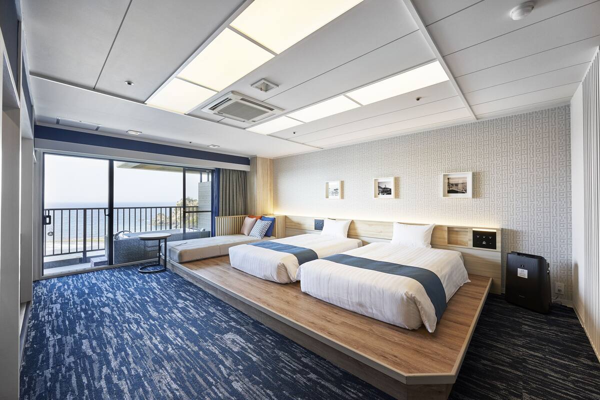 Ein Hotelzimmer mit zwei Betten, einem Balkon und Meerblick.