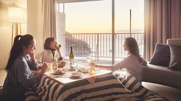 Un comedor con una mesa dispuesta para tres personas, un sofá y vistas al mar a través de amplias ventanas.