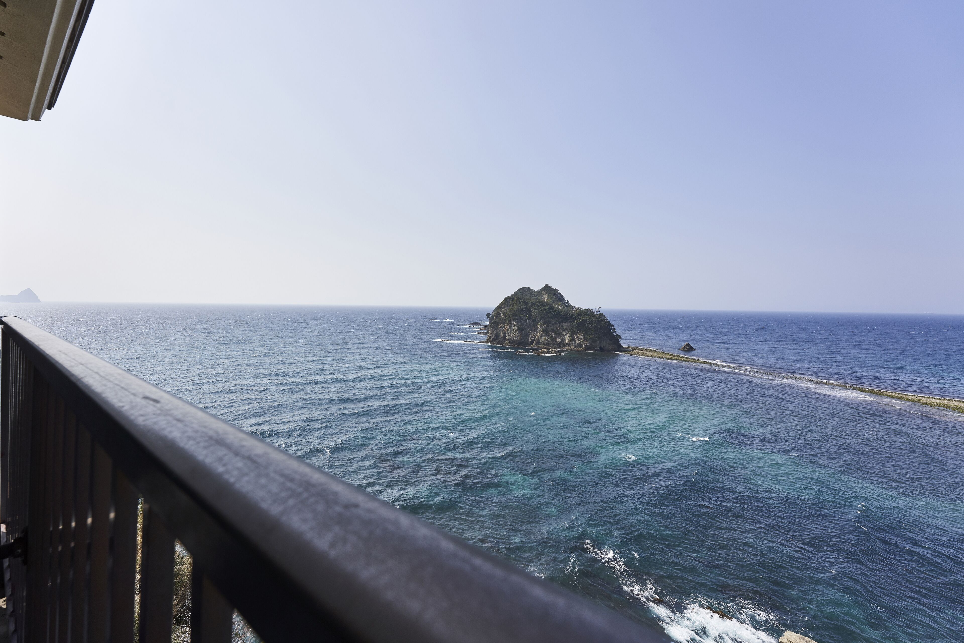 A view of the ocean with a rocky island and a sandy beach.
