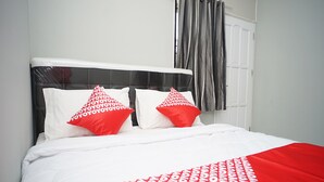 A bed with a white and red patterned bedspread, two red pillows with white text, and a black headboard. - OYO 1007 Alletha Guest House 2 (Balikpapan)