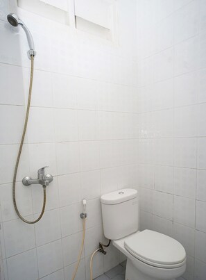 Ein kleines Badezimmer mit weißen Fliesen, einer Toilette und einer Dusche.