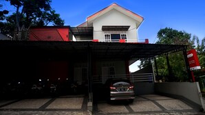 A building with a red roof and white walls, a covered parking area, and a signboard. - OYO 1007 Alletha Guest House 2 (Balikpapan)