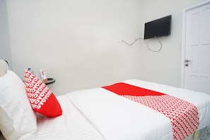Ein Hotelzimmer mit Bett, Wandfernseher und einer weißen Tür.