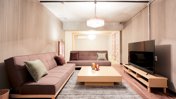 Een moderne woonkamer met een bruine bank, een houten salontafel en een televisie op een houten dressoir.