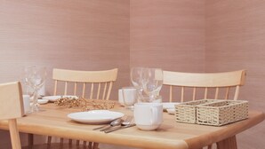 Een eettafel gedekt met witte borden, glazen en bestek, omringd door houten stoelen.