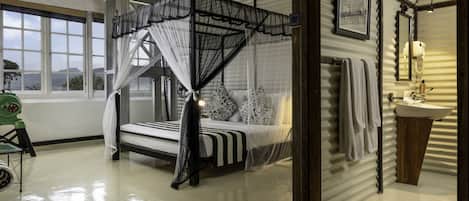 Un dormitorio con cama con dosel, una ventana con vistas, un lavabo y un espejo.