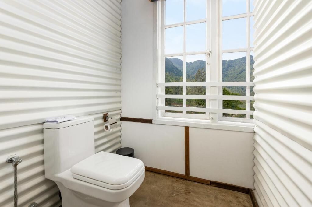 Ein kleines Badezimmer mit Toilette, einem Fenster und Bergblick.