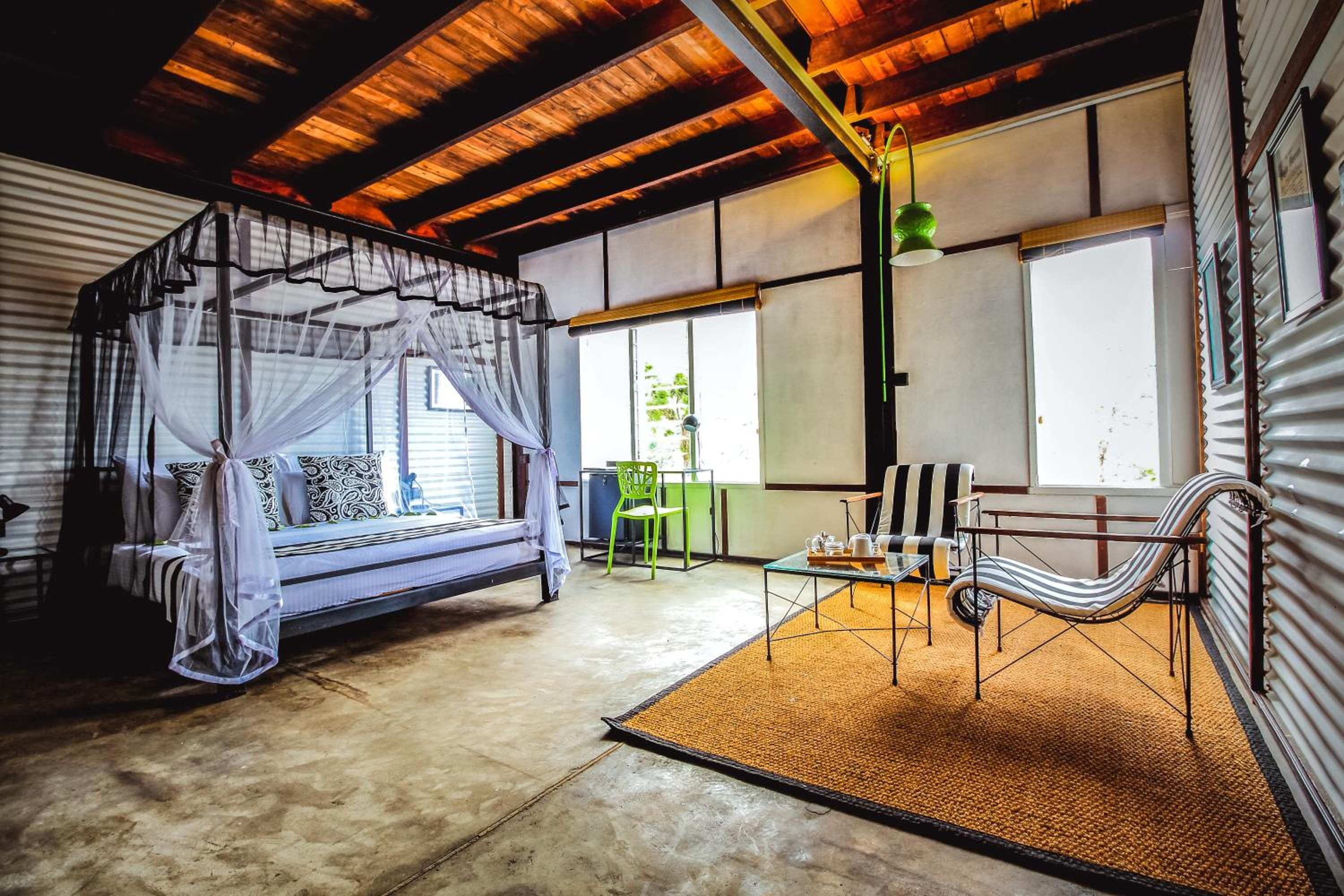 A room with a bed, a chair, a table, and a window.