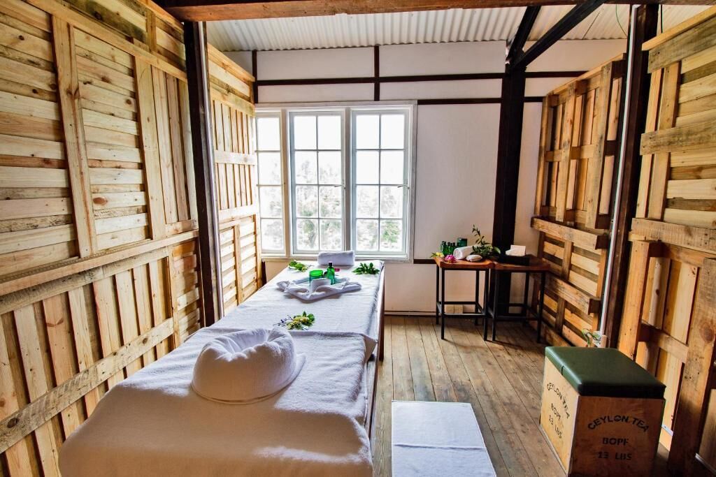 Una habitación de madera con una cama, una mesita y una ventana.