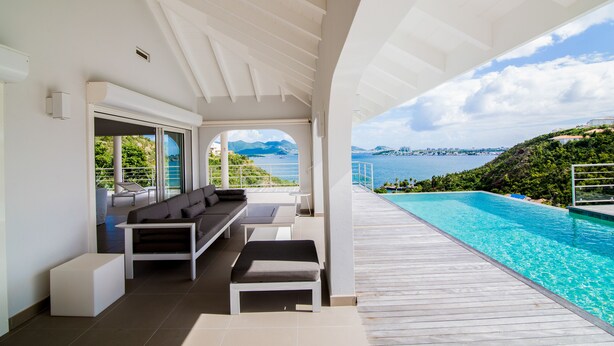 Ein moderner Außenbereich mit Lounge-Möbeln, Pool und einem schönen Meerblick.