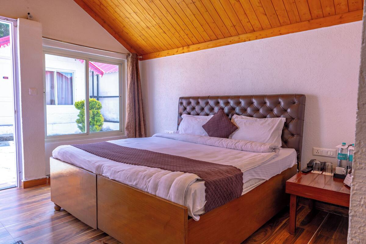 A bedroom with a wooden bed, a nightstand, and a window with curtains.