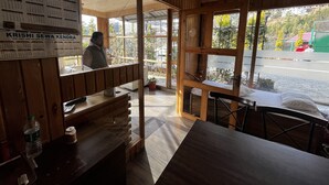 Interno di un ristorante con pannelli in legno, un bancone e vista sulla strada.