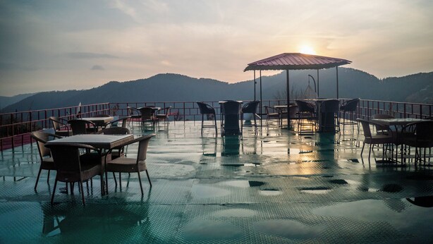 Una terrazza con tavoli e sedie, una zona relax coperta e vista su dolci colline.