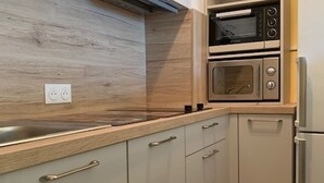 Eine moderne Küche mit Holzschränken, einer eingebauten Mikrowelle und einem Edelstahl-Kühlschrank.