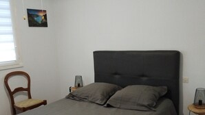 Ein Schlafzimmer mit einem Bett, einem Sessel, einem Nachttisch und einem Wandbild.