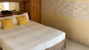 Un dormitorio con cama, armario de madera y un panel decorativo en la pared.