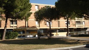 Un edificio de varios pisos con fachada de ladrillo, varias ventanas y un letrero que dice 'MARC COIFFURE'.