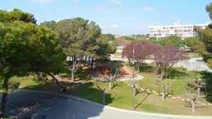 Un parque con juegos infantiles, árboles y un edificio al fondo.