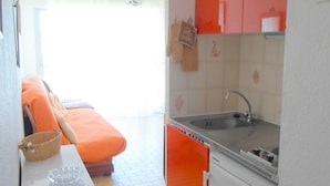 Een kleine keuken met een spoelbak, een tafeltje en een stoel.